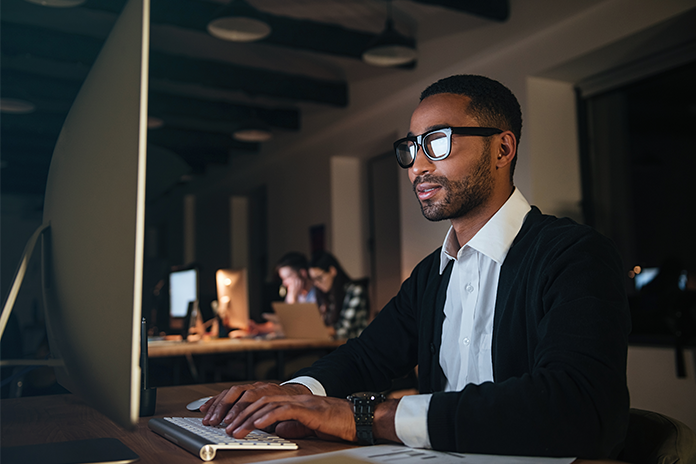 dark skinned business man working late night in office with computer